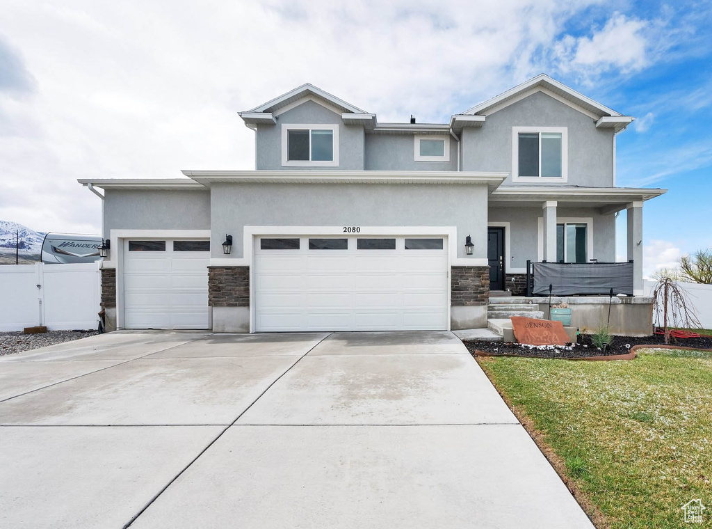 View of front of property with stone siding, stucco siding, driveway, and covered porch