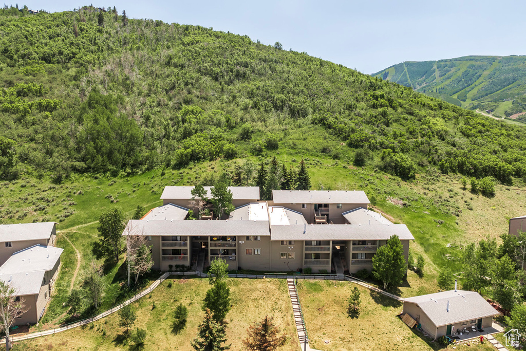 Aerial view of property and surrounding area with a heavily wooded area and a mountain backdrop