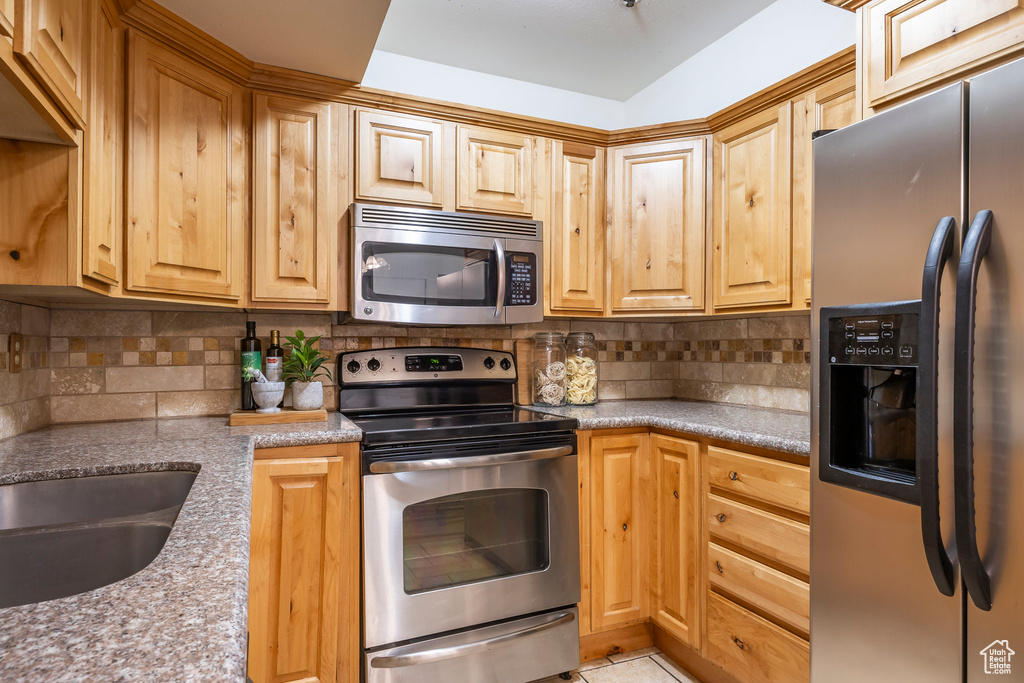 Kitchen with appliances with stainless steel finishes and decorative backsplash