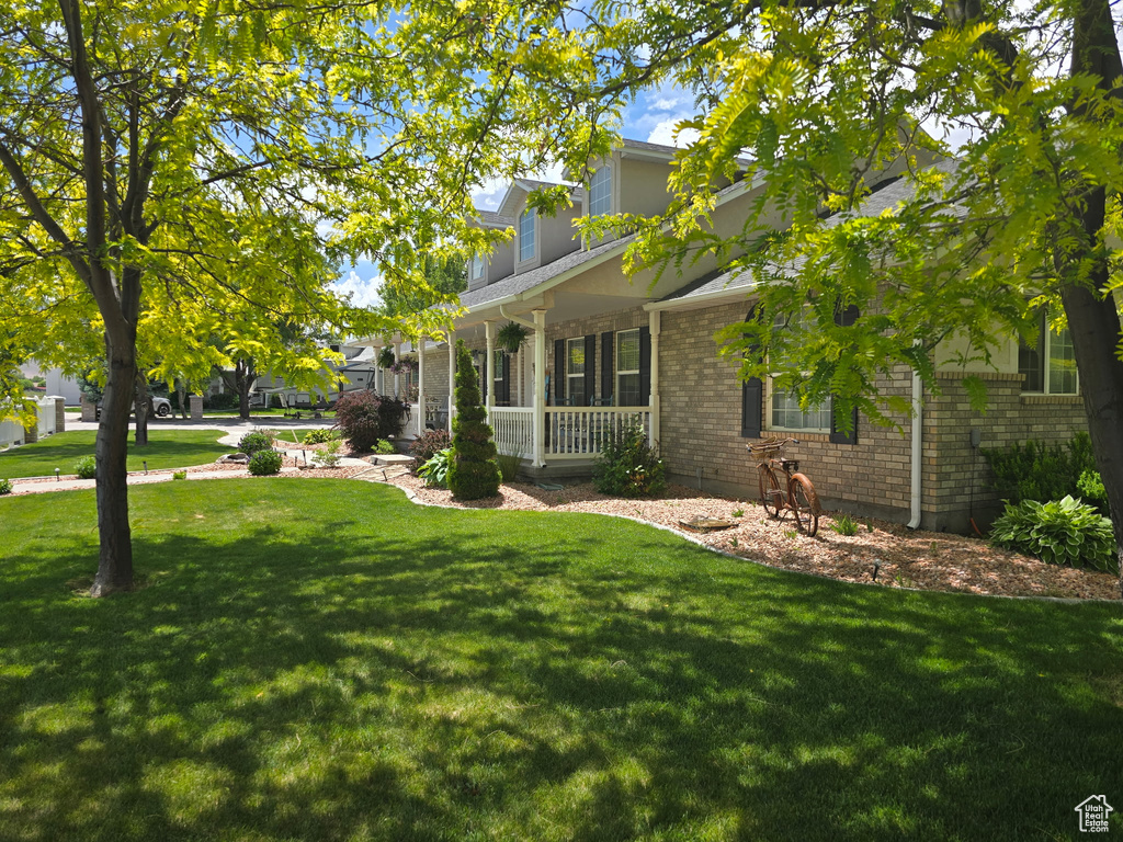View of property exterior with a porch, a lawn, and brick siding