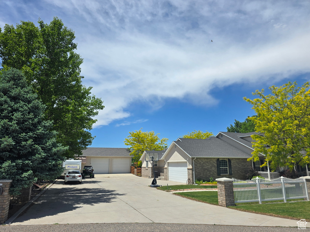 View of front of house featuring a detached garage, brick siding, and roof with shingles