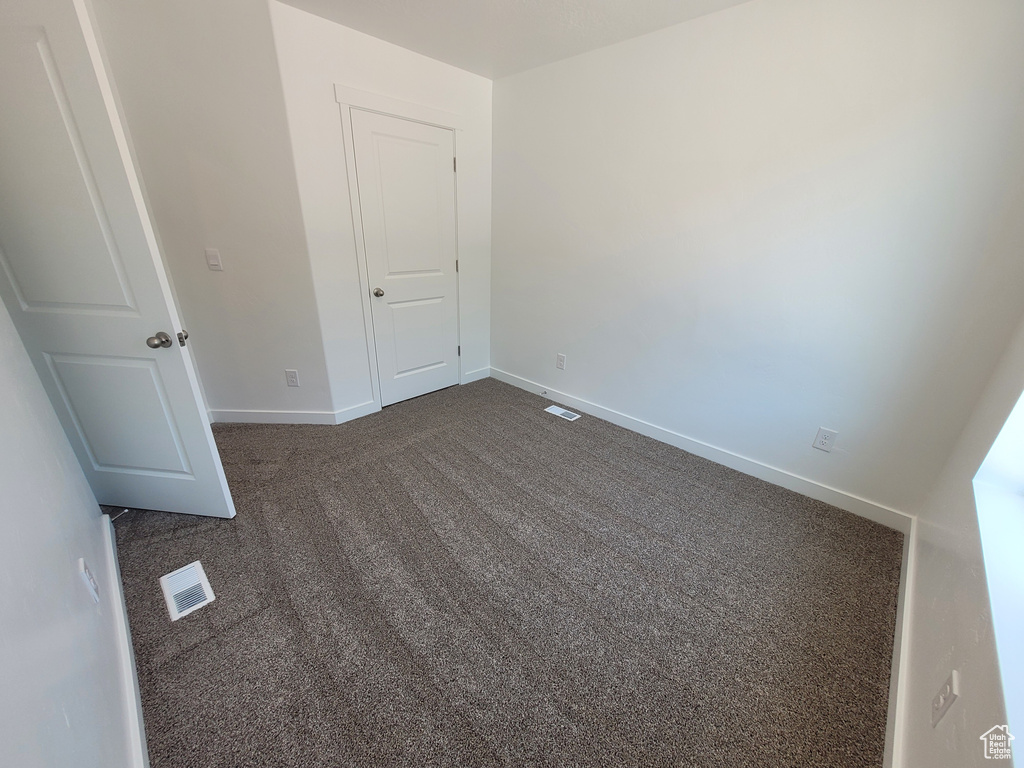 Empty room featuring dark colored carpet and baseboards