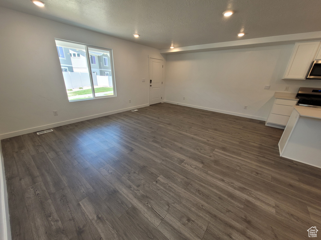 Unfurnished living room with dark wood-style flooring, recessed lighting, and a textured ceiling