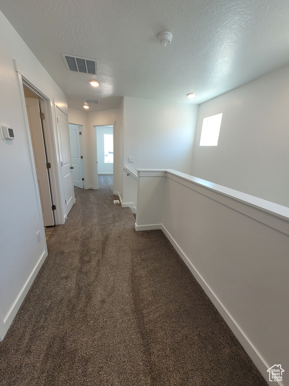 Corridor featuring an upstairs landing, carpet flooring, and a textured ceiling