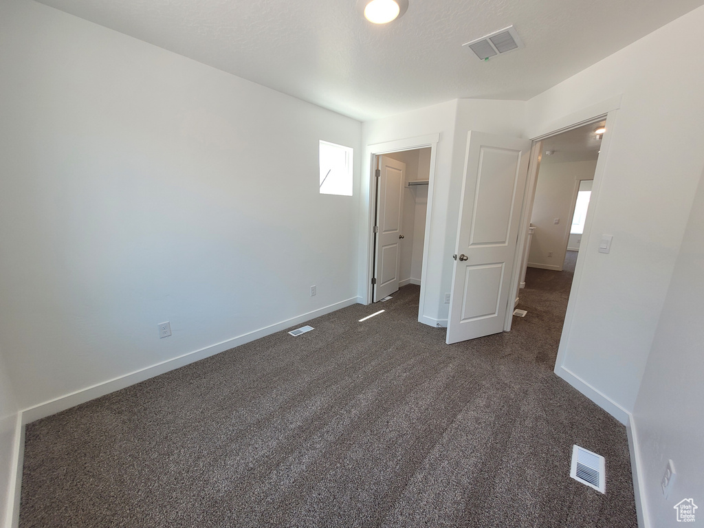 Unfurnished bedroom with dark carpet and a spacious closet