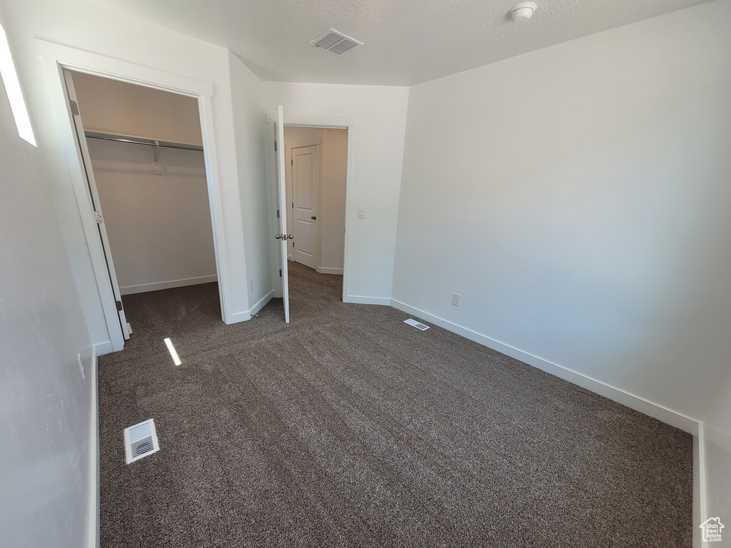 Unfurnished bedroom featuring dark carpet and a closet