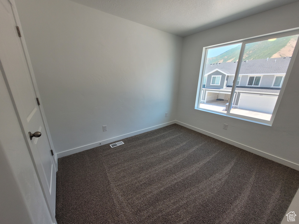 Unfurnished room with dark carpet and baseboards