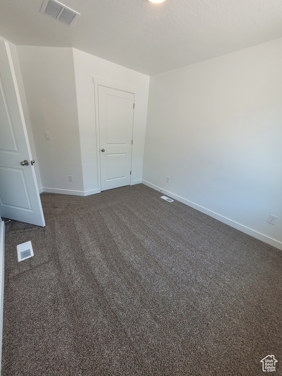 Unfurnished room featuring baseboards and dark carpet
