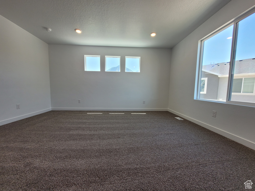 Spare room featuring dark colored carpet and recessed lighting