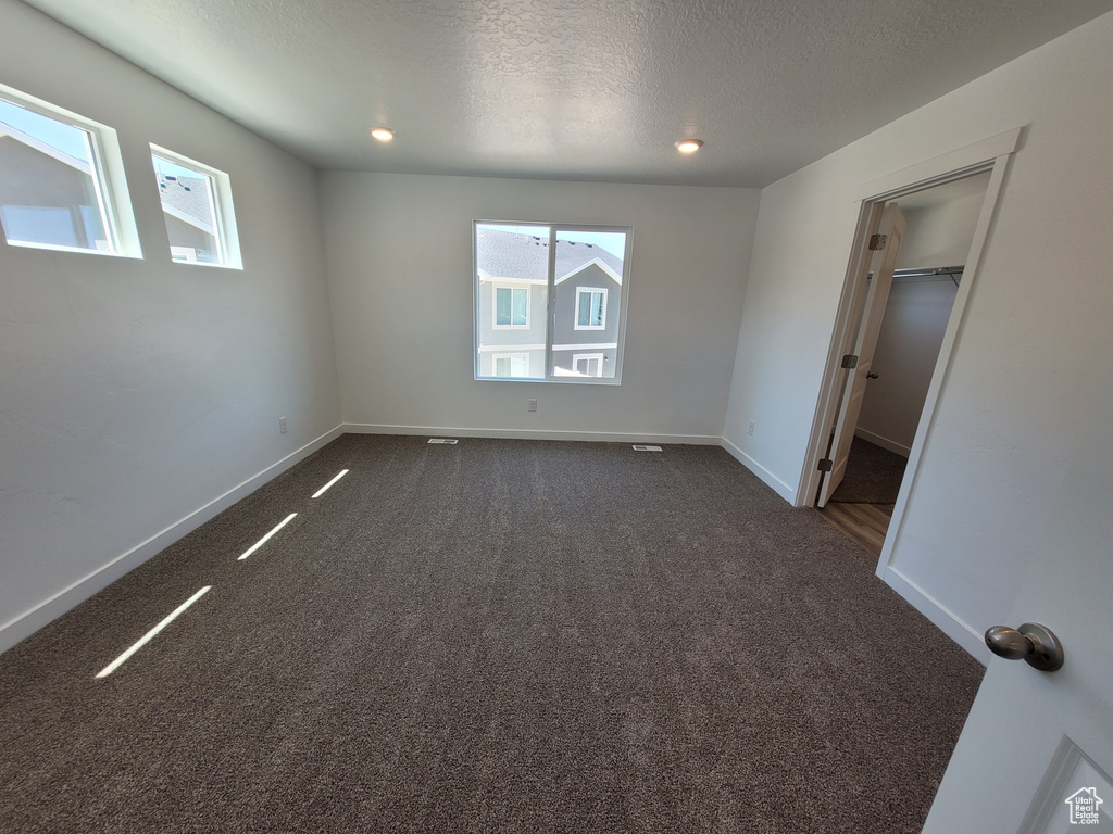 Unfurnished room featuring dark carpet and a textured ceiling