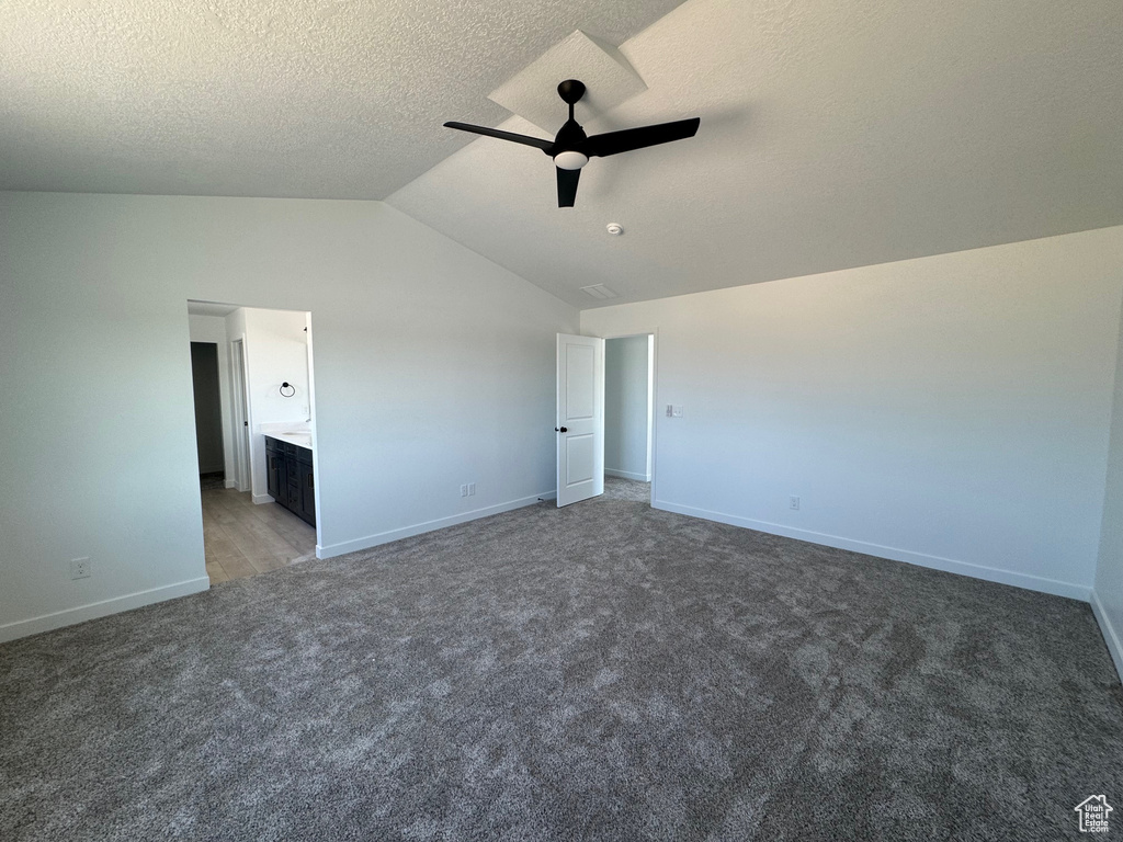 Unfurnished bedroom with vaulted ceiling, baseboards, light carpet, a textured ceiling, and a ceiling fan