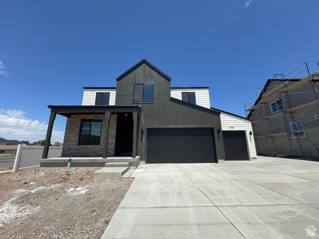 View of front of home with concrete driveway, an attached garage, and covered porch