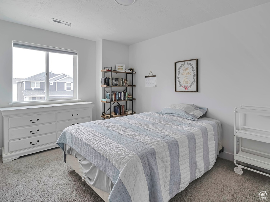 Bedroom with baseboards, a textured ceiling, visible vents, and light carpet