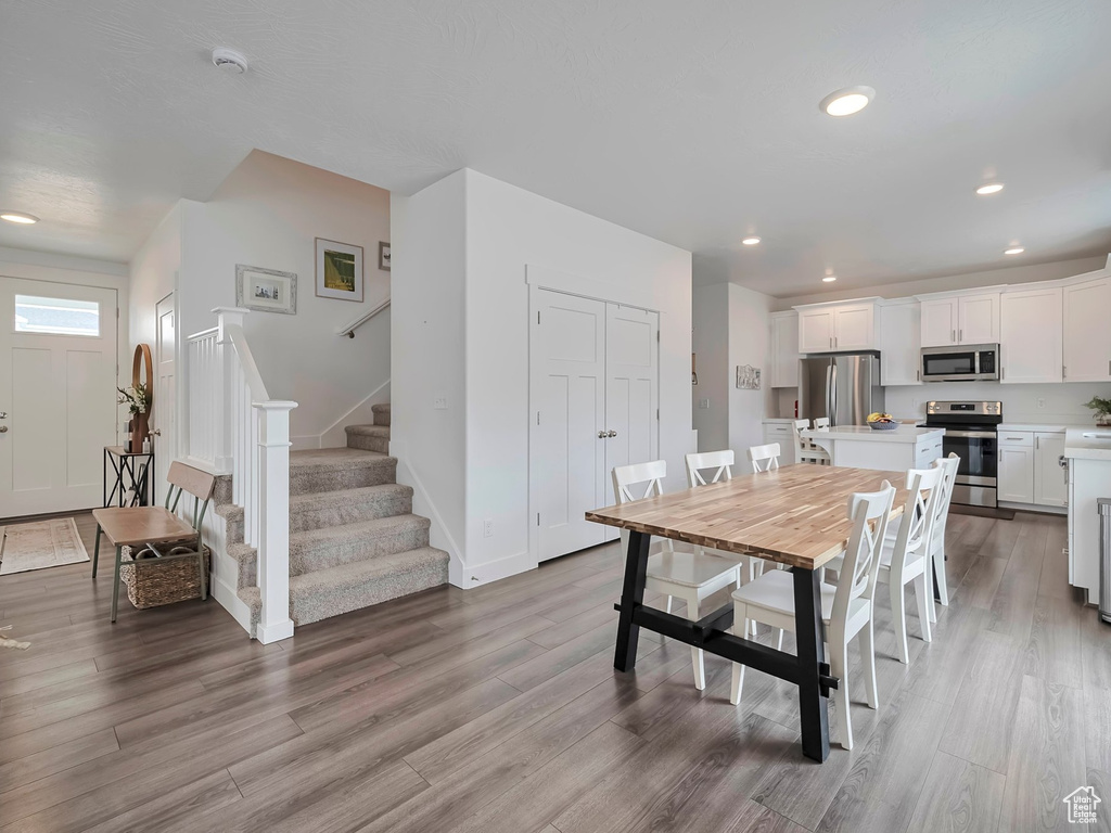 Dining space with baseboards, stairs, wood finished floors, and recessed lighting
