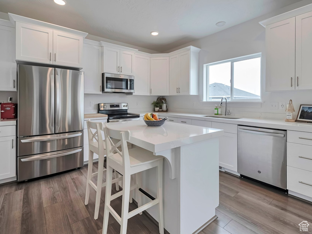 Kitchen featuring dark wood-type flooring, white cabinetry, a sink, and stainless steel appliances