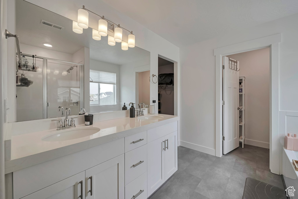 Full bathroom featuring a shower stall, double vanity, visible vents, and a sink