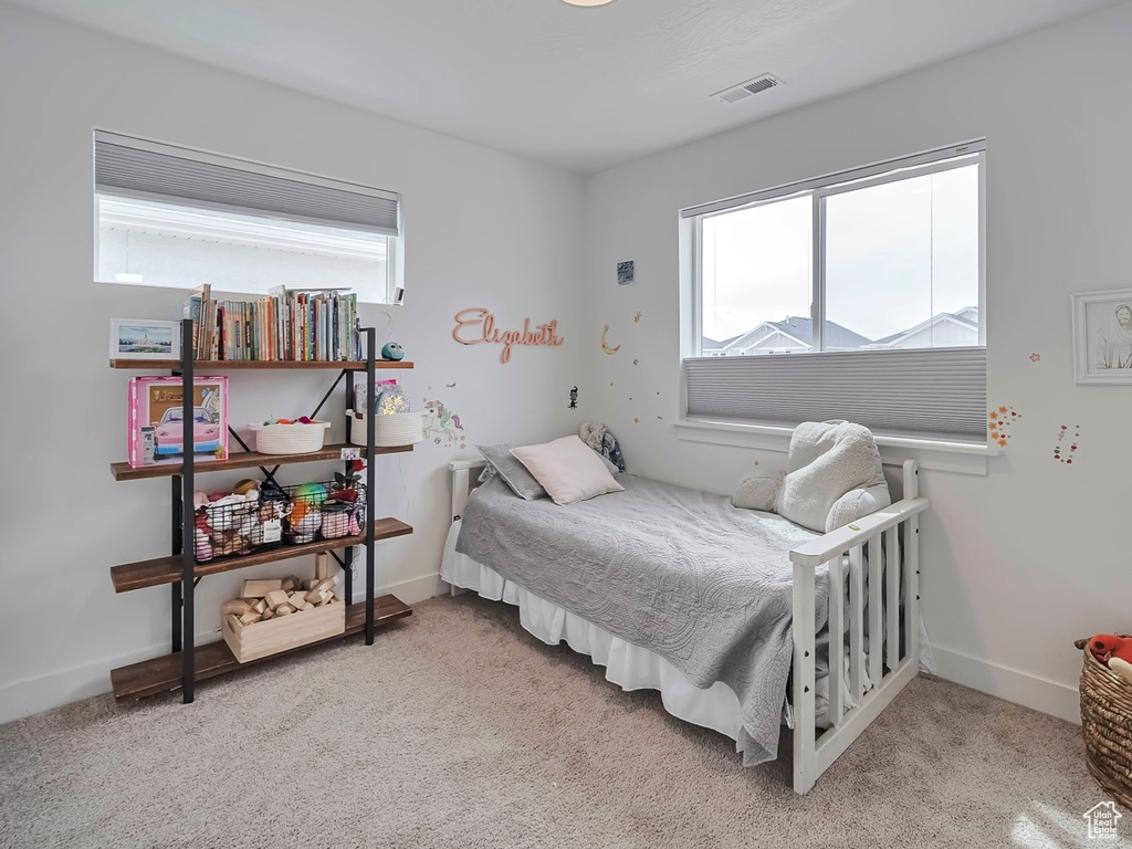 Bedroom featuring light carpet, multiple windows, and visible vents