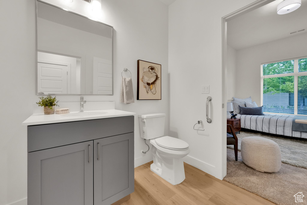 Bathroom with wood finished floors, toilet, vanity, baseboards, and connected bathroom