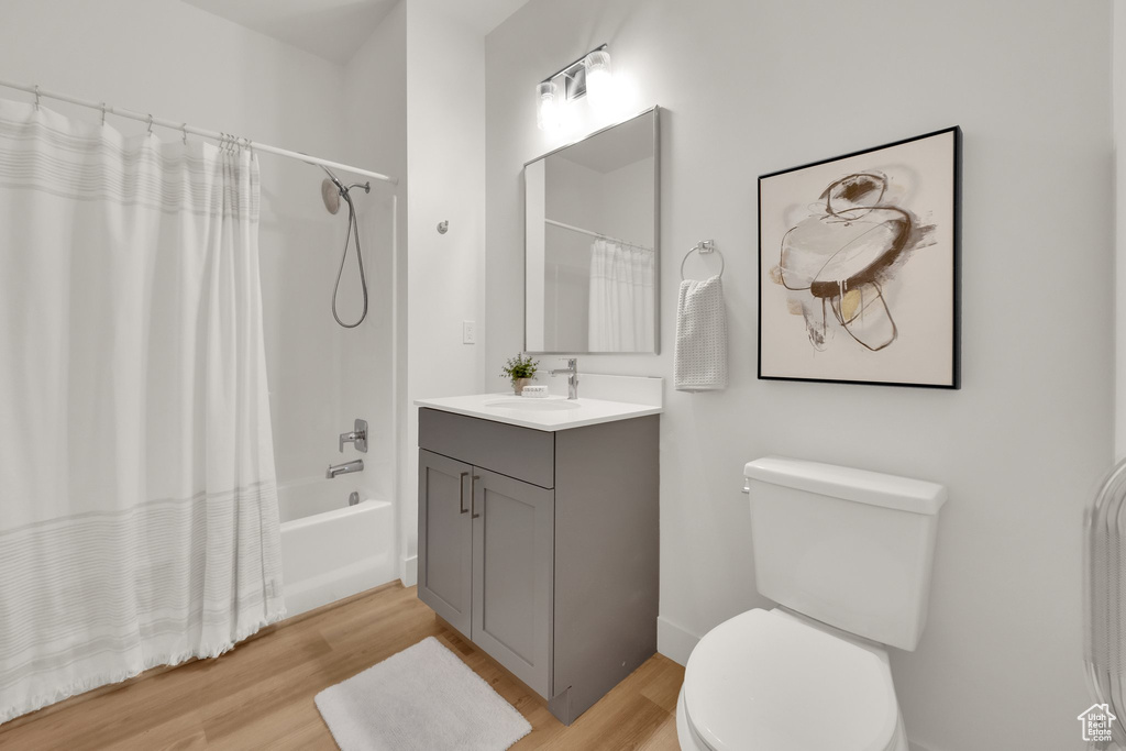 Bathroom with wood finished floors, toilet, vanity, and shower / tub combo