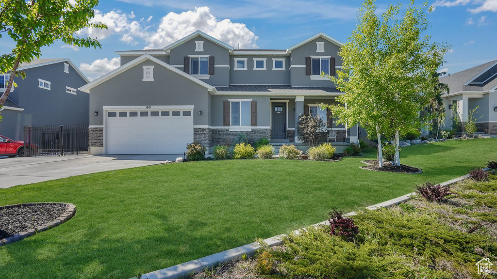 Craftsman inspired home with driveway, a garage, a front lawn, stone siding, and stucco siding