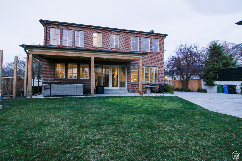 Rear view of property featuring brick siding, fence, and a lawn