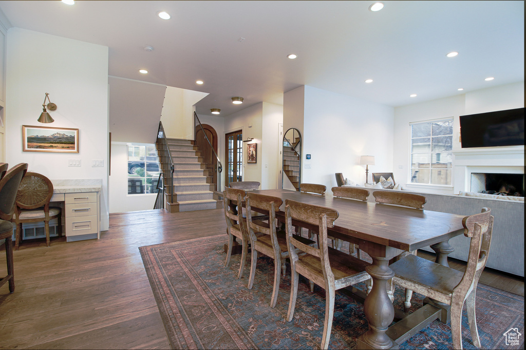 Dining area featuring a fireplace, dark wood-type flooring, stairs, and recessed lighting