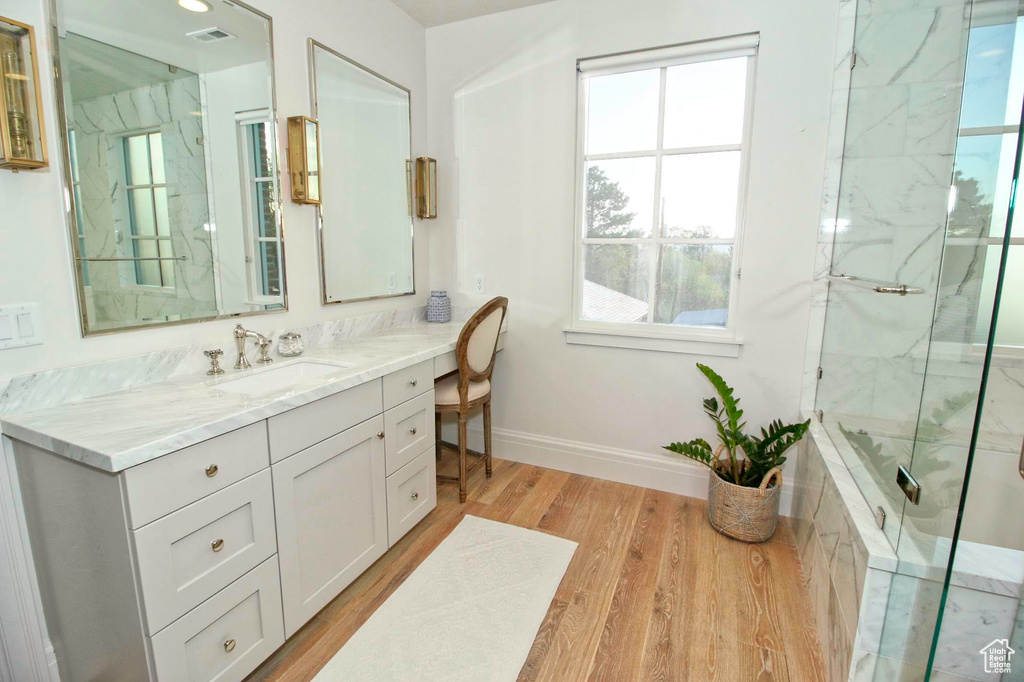 Bathroom with visible vents, baseboards, a marble finish shower, wood finished floors, and vanity