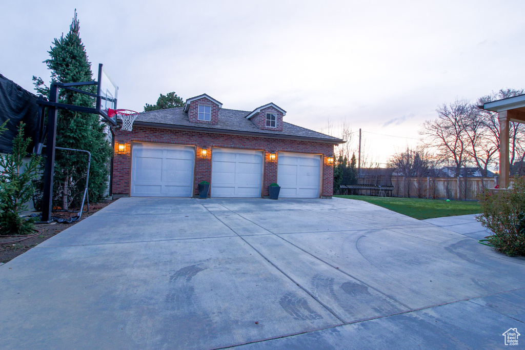 Garage featuring fence and concrete driveway