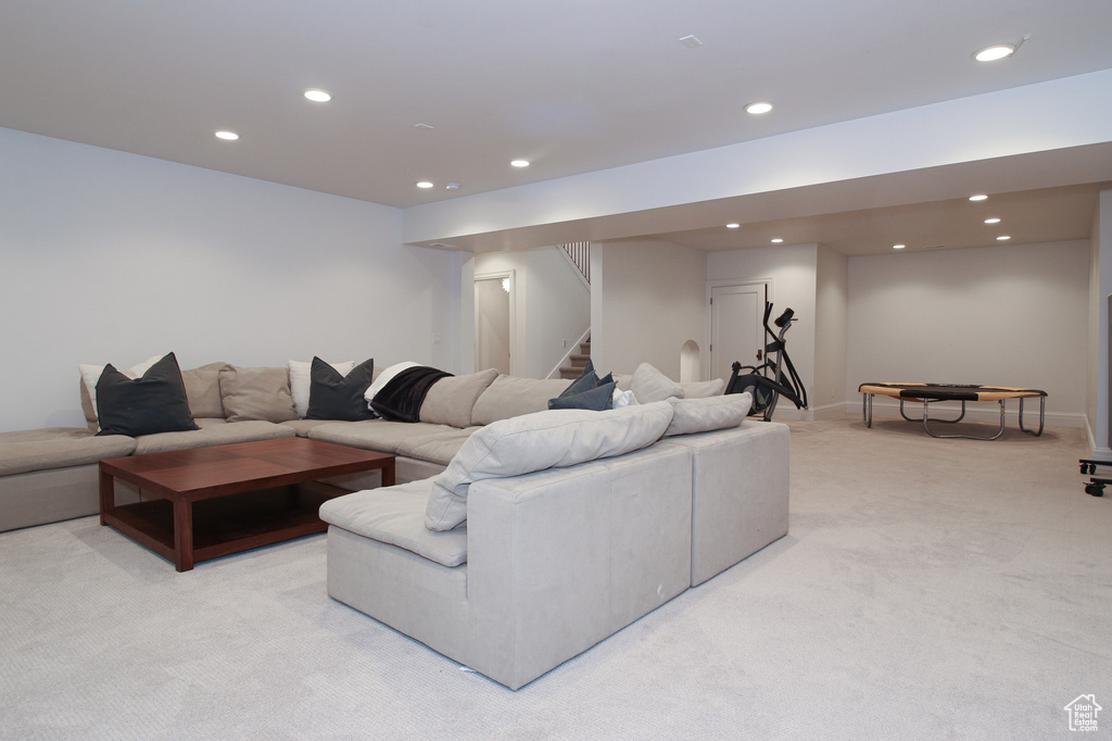 Living area featuring baseboards, stairway, light colored carpet, and recessed lighting