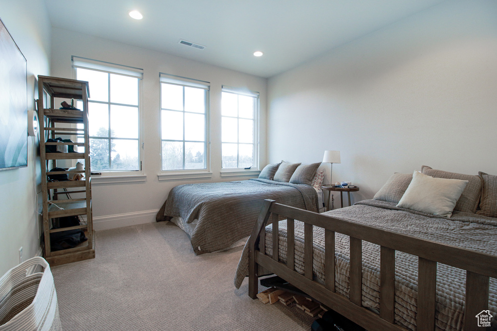 Bedroom featuring baseboards, visible vents, multiple windows, and light carpet
