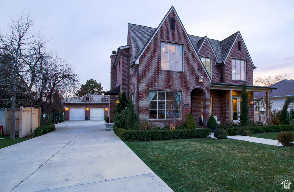 English style home with an outbuilding, brick siding, a garage, a yard, and a chimney