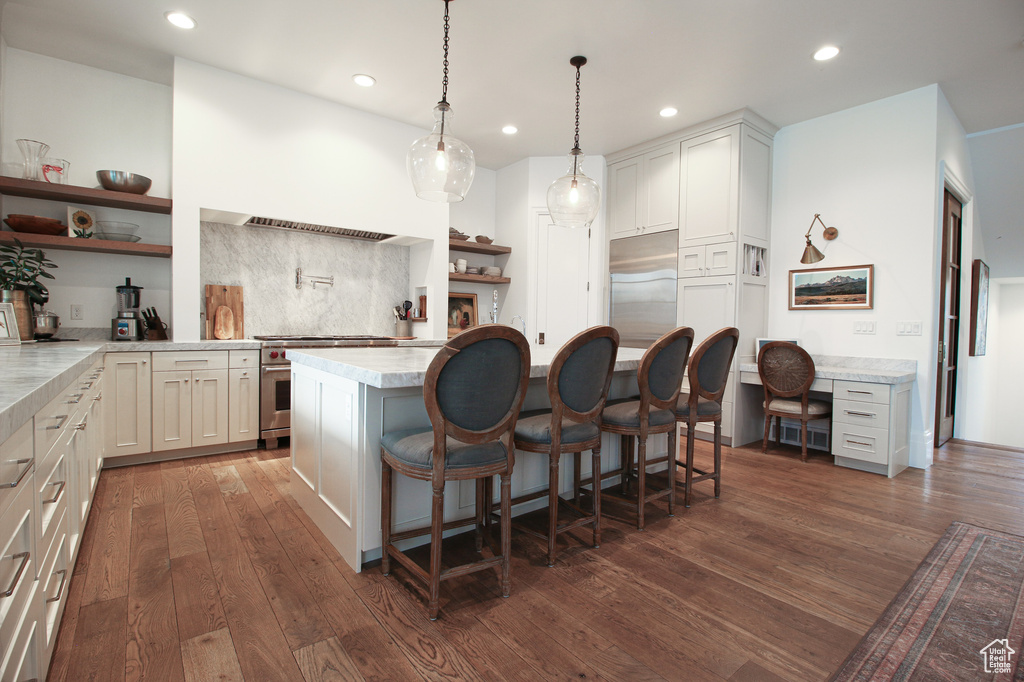 Kitchen with stainless steel stove, light countertops, a breakfast bar, dark wood-type flooring, and open shelves