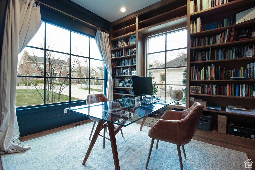Office area with built in shelves, wood finished floors, and bookshelves