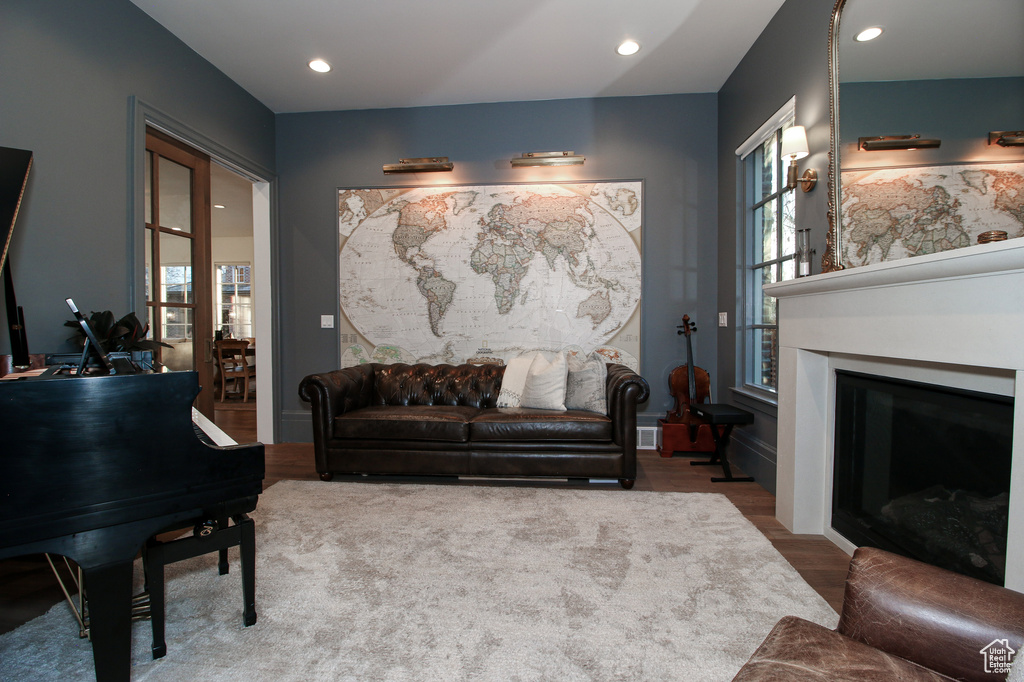 Living room with recessed lighting, a fireplace with flush hearth, and wood finished floors