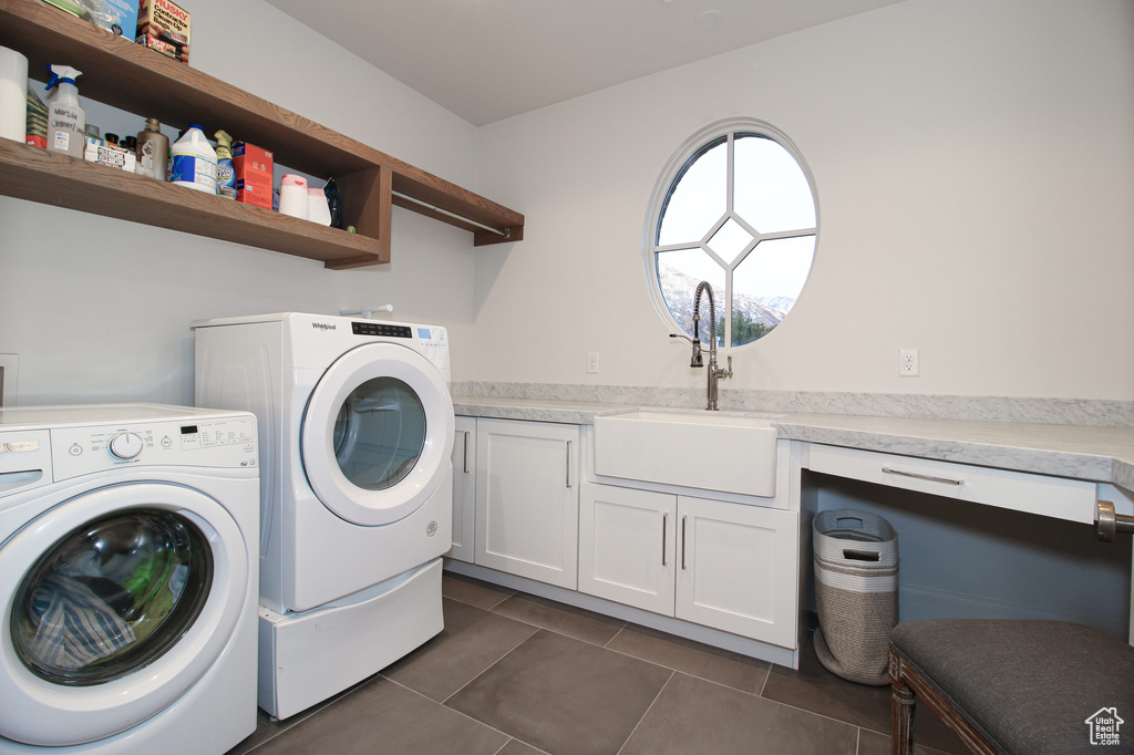Washroom featuring dark tile patterned floors, separate washer and dryer, cabinet space, and a sink