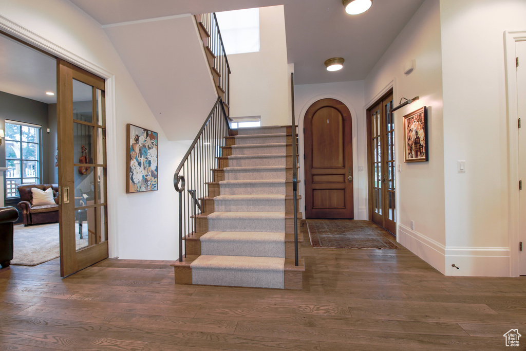 Foyer featuring baseboards, stairway, wood finished floors, and french doors