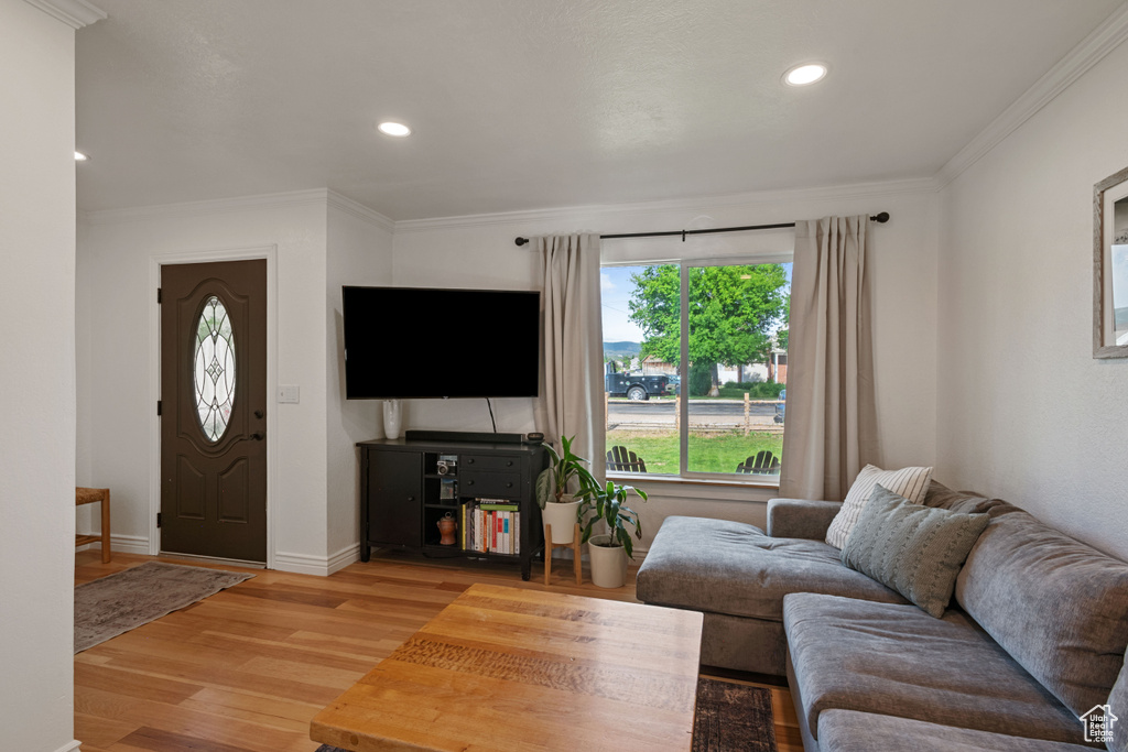 Living room featuring crown molding, light wood-style floors, recessed lighting, and baseboards