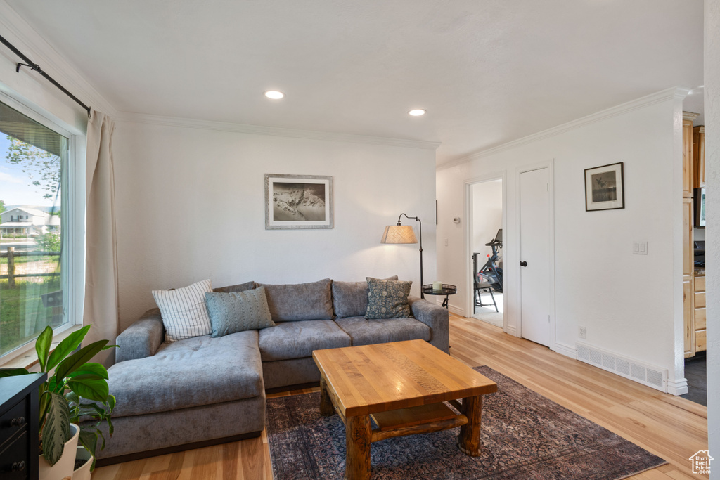 Living room featuring wood finished floors, crown molding, recessed lighting, and baseboards