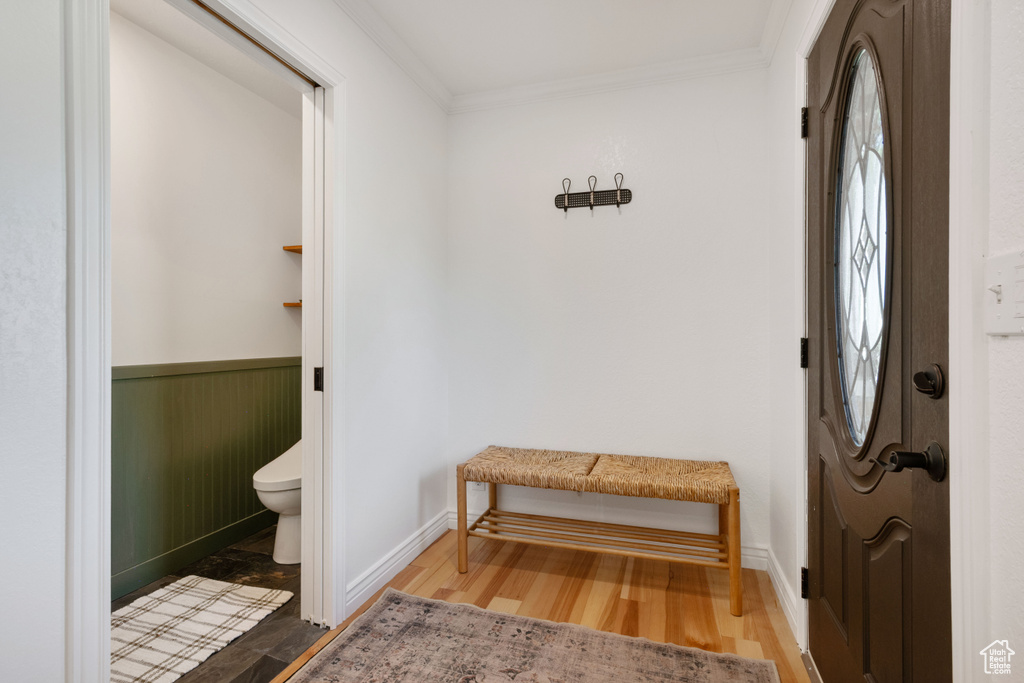 Foyer entrance with ornamental molding, wood finished floors, and baseboards