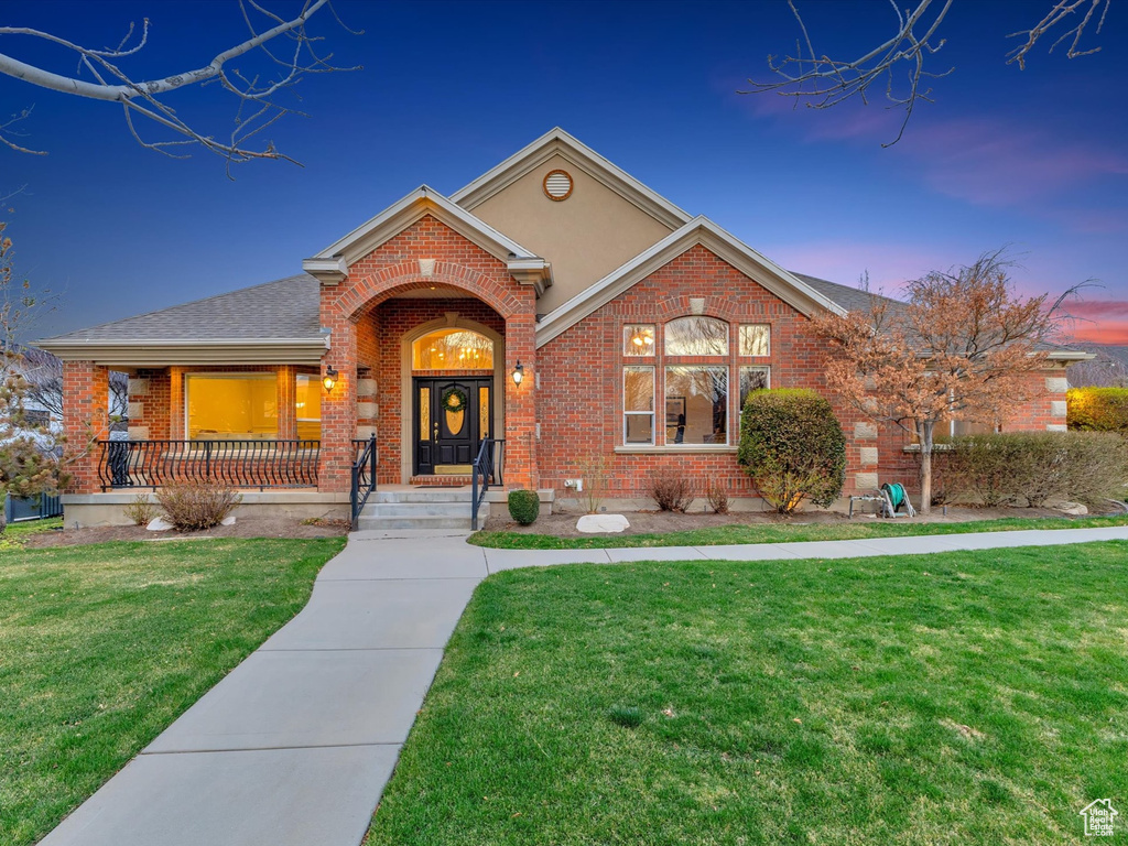 Traditional-style home featuring brick siding, a front lawn, and covered porch