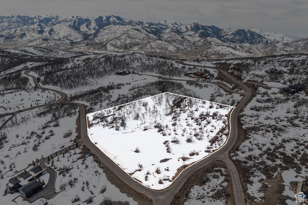 Snowy aerial view featuring property parcel outlined and a mountain view