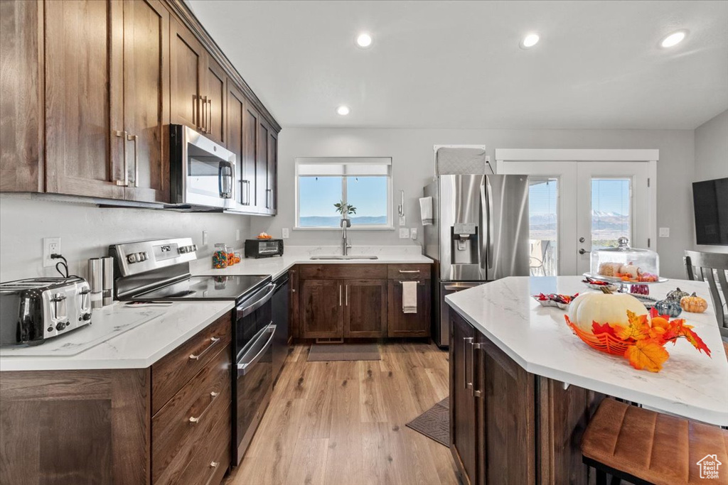 Kitchen featuring appliances with stainless steel finishes, french doors, a sink, light wood-style flooring, and recessed lighting