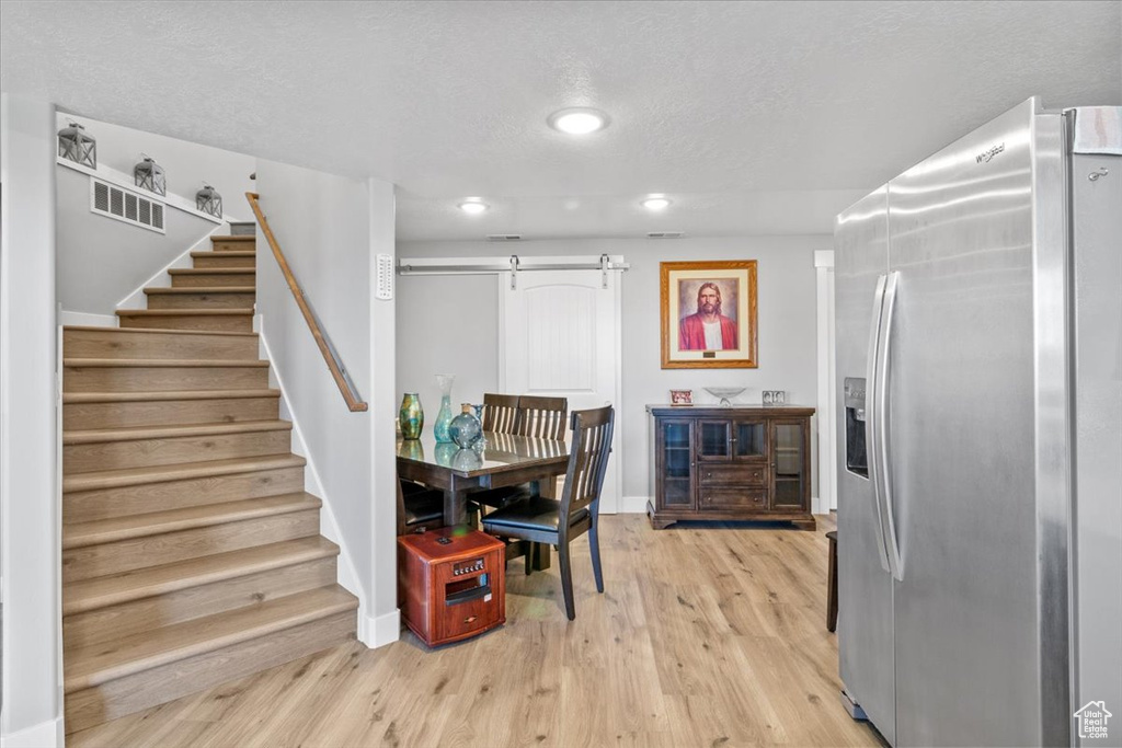 Dining space with a barn door, stairway, light wood-style floors, recessed lighting, and baseboards