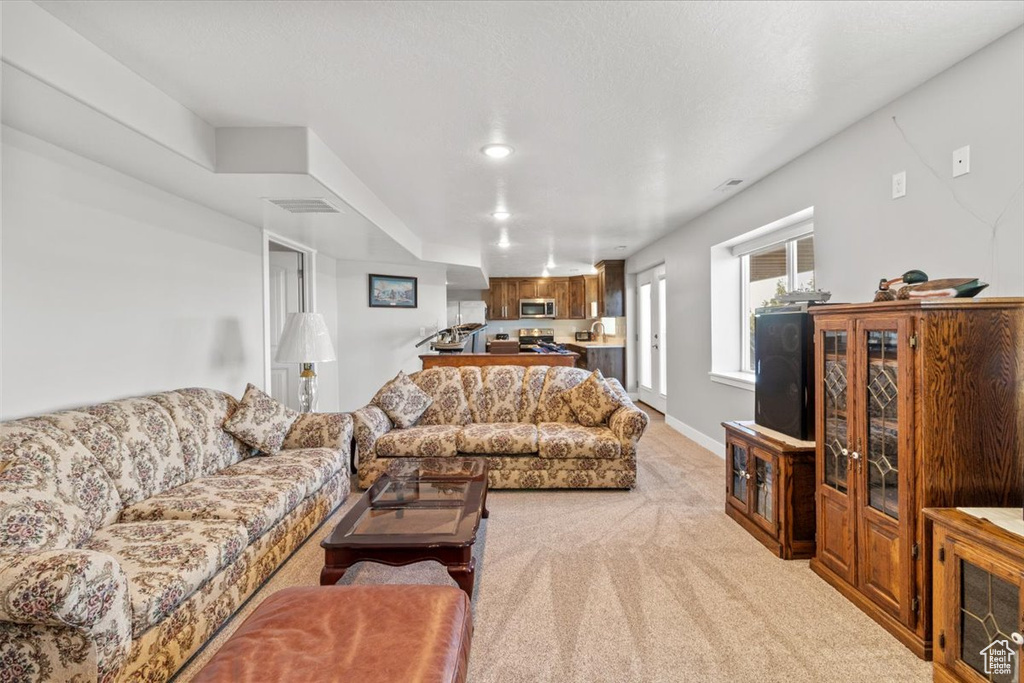 Living area with light colored carpet, recessed lighting, and baseboards