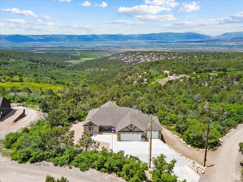 Aerial view of property and surrounding area with a forest and a mountain backdrop