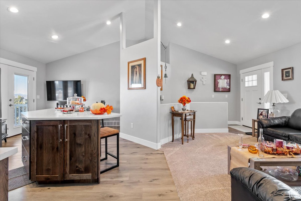 Living area with lofted ceiling, healthy amount of natural light, light wood-type flooring, recessed lighting, and baseboards