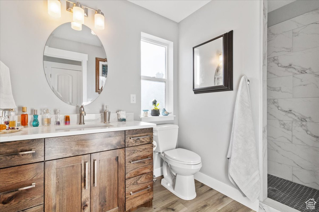 Full bathroom with vanity, baseboards, a marble finish shower, toilet, and wood finished floors
