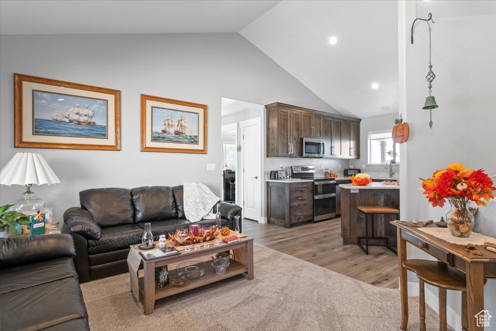 Living room featuring high vaulted ceiling, light wood-style flooring, and recessed lighting