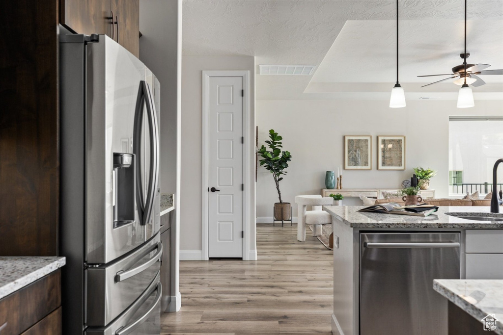 Kitchen featuring stainless steel appliances, a sink, ceiling fan, light wood finished floors, and dark brown cabinets