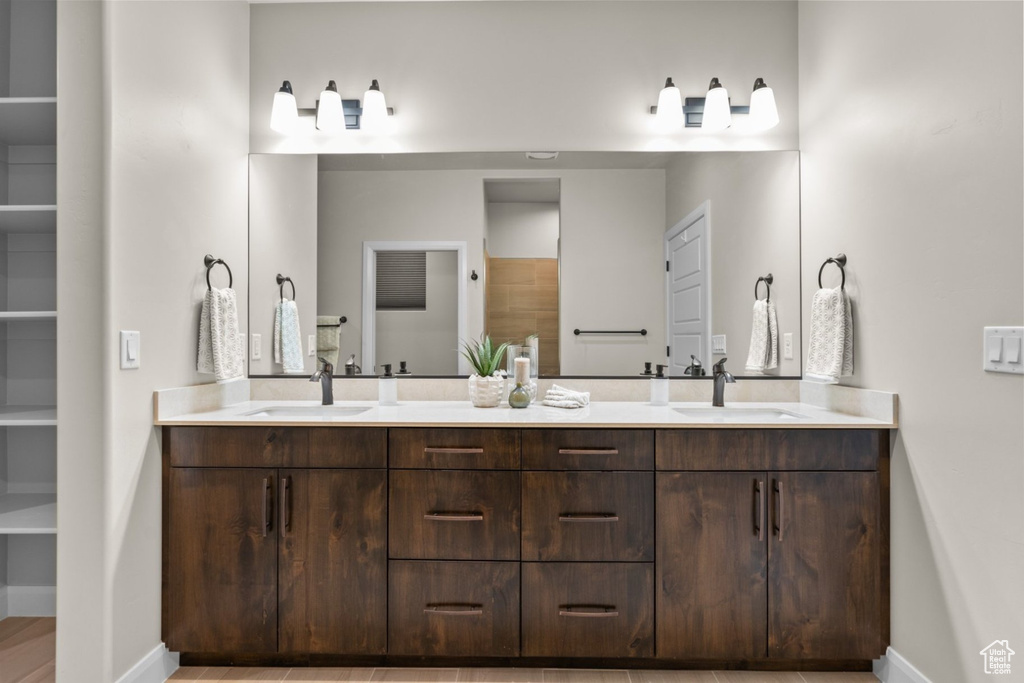 Bathroom featuring baseboards, double vanity, and a closet